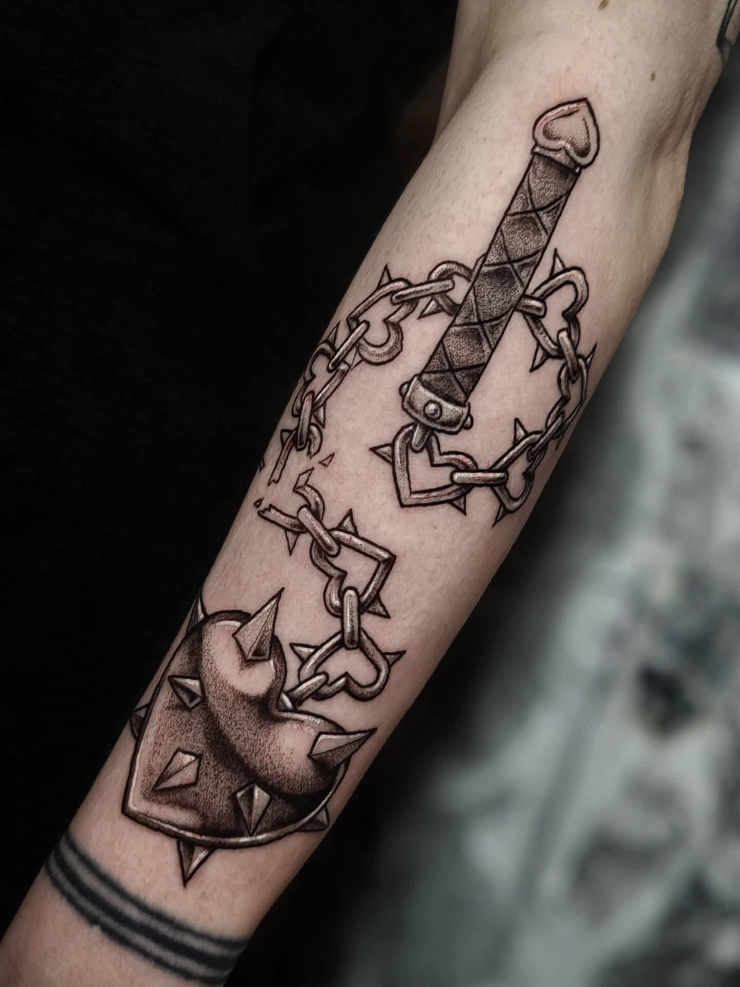 Black and white tattoo of a heart shaped flail