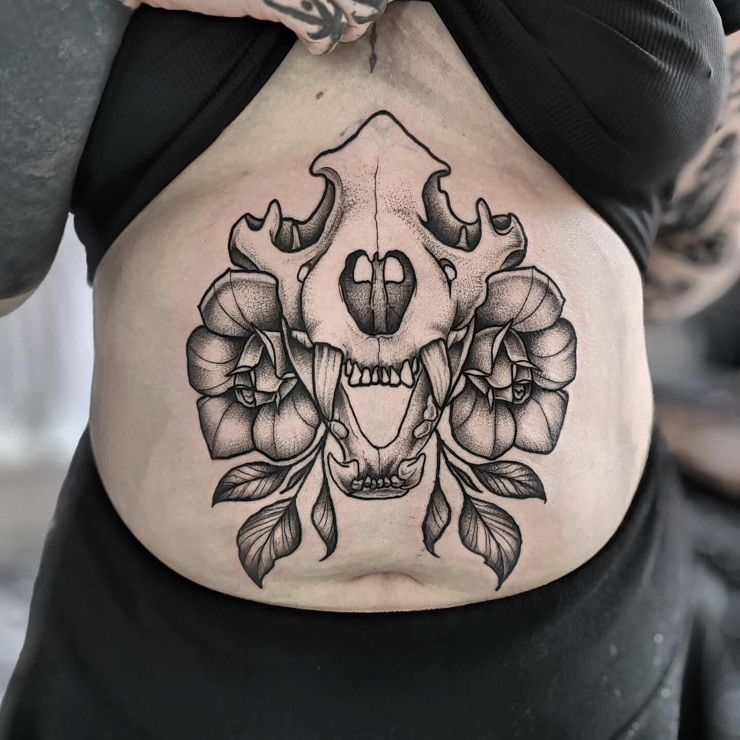 Blackwork piece of a skull with flowers on a sternum