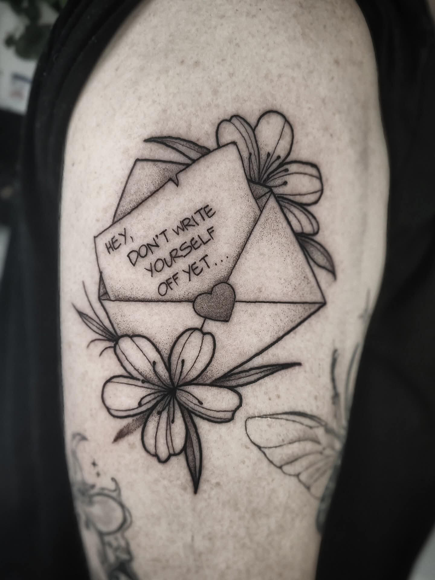 Black and white tattoo of an envelope with a letter and flowera